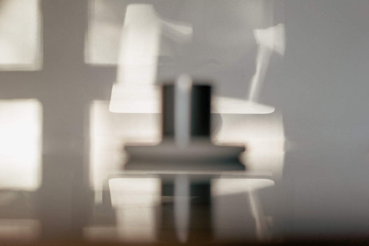 Blurred image of a modern interior with a Babel candle and a table with the sun shining through on the wall.